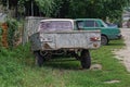An one old gray metal trailer stands on green grass near a wooden fence Royalty Free Stock Photo