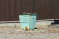 One old green iron trash can in rust stands on gray asphalt Royalty Free Stock Photo