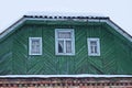 One old green wooden attic of a rural house with three small windows with a roof