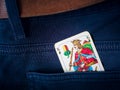 One old king card from deck of playing cards with german suit - acorn, in pocket of blue pants