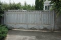 One old large gray closed metal gate and part of the fence