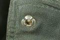 One old metallic gray rivet button on the black leather