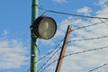 One old round spotlight with a lamp on an iron pole at the fence Royalty Free Stock Photo