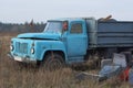 One old truck with a blue cabin is standing in the dry grass Royalty Free Stock Photo