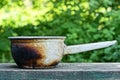one old white enamelled dirty metal saucepan burnt and covered in black soot