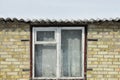 One old window on a brown brick wall under a roof Royalty Free Stock Photo