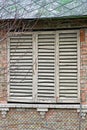 One old window closed with wooden white shutters on a brown brick wall Royalty Free Stock Photo