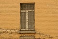 Old window with an iron grill on a brick brown wall Royalty Free Stock Photo