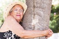 One old woman hug a tree at the park. Love nature feeling and healthy natural lifestyle concept old female people. Happiness and Royalty Free Stock Photo