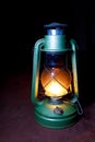 Old worn kerosene lamp green is in the dark of night on Burgundy background