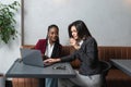 One-on-one meeting.Two young business women sitting at table in cafe. Girl shows colleague information on laptop screen. Girl Royalty Free Stock Photo
