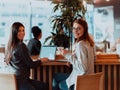 two young business women sitting at table in cafe. Girl shows colleague information on laptop screen. Girl using Royalty Free Stock Photo