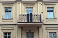 One open black iron balcony with a wrought pattern on a brown brick wall with windows Royalty Free Stock Photo