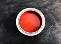 One open can with beautiful red paint stands on a black matte wooden background.