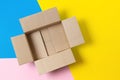 One open empty cardboard box on geometric pink, blue, yellow background. Top view Royalty Free Stock Photo