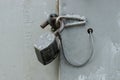 One open large iron padlock hanging on a gray metal door