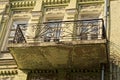 One open old balcony with black iron bars with a forged pattern on the gray concrete wall