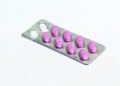 One open package of pink oblong pills isolated on a white background