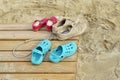 Adult and childrens` shoes on wooden boardwalk with sand at beach