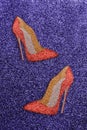 Women red shoes with glitter on a purple glittery background