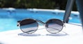One pair of sunglasses near swimming pool outdoors Royalty Free Stock Photo