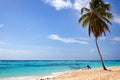 One palm tree on the beach with white sand, boat at the shore, blue sea and sky with clouds background Royalty Free Stock Photo