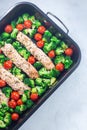 One pan dish, baked salmon fillet with broccoli and tomato on frying tray, vertical, top view Royalty Free Stock Photo