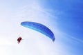 Paraglider with blue wing flying in blue sky Royalty Free Stock Photo