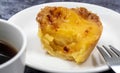 One Pastel de nata or Portuguese egg tart on a white plate. Pastel de Belm is a small pie with a crispy puff pastry