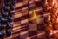 One pawn staying against full set of black chess pieces. Closeup of chessboard with wooden pieces on table in sunlight, game of Royalty Free Stock Photo