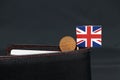 One Penny British decimal coin money and mini Union Jack flag stick on the black wallet with dark background Royalty Free Stock Photo