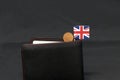 One Penny British decimal coin money and mini Union Jack flag stick on the black wallet with dark background Royalty Free Stock Photo