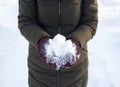 One person holds a snowball in winter in the Park, walk, fun, sports and leisure, green jacket, Burgundy mittens