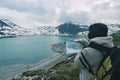 One person looking at trekking map, dramatic sky at dusk, lake and snowy mountains, nordic cold feeling