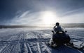 One person ready to drive snowmobile in very cold mountains in Sweden, frosty fog around bright sun creates halo effect, birches Royalty Free Stock Photo