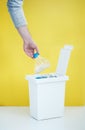 One person sorts recyclable materials on a yellow background into a special bin