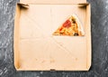 One piece of pizza in cardboard pizza box Top view of empty box with copy space on dark concrete