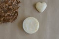 One piece of round natural handmade soap, dry flower of buldenezh and souvenir heart on craft paper. Aromatherapy, skin care.