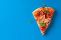 One piece of salami pizza on blue background. Top view and copy Royalty Free Stock Photo