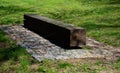 One piece of wood made prism park bench painted brown footsteps concrete rectangles gray in the lawn Royalty Free Stock Photo