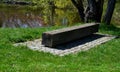 One piece of wood made prism park bench painted brown footsteps concrete rectangles gray in the lawn Royalty Free Stock Photo