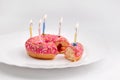 Pink donut on white plate like birthday cake with candles on white background Royalty Free Stock Photo