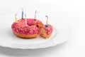 Pink donut on white plate like birthday cake with candles on white background Royalty Free Stock Photo