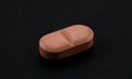 One pink pill of pharmaceutical medicine on a black background. Cure for the disease. Close-up of a medical drug. Macro Royalty Free Stock Photo