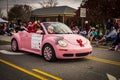 One pink small car with eye lashes driving through a Christmas parade