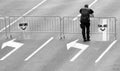 One policeman and two shields leaned on temporary barricade fence on city street in black and white