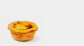 One Portuguese Pastel de Nata pie with custard and cinnamon sticks on a white plate. Pastel de Belem is an iconic cup