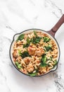 One pot lunch. Orzo pasta with meatballs and spinach in tomato sauce in a frying pan on a light background, top view Royalty Free Stock Photo