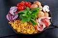 One pot pan pasta with bacon, chestnut mushrooms, cherry tomatoes, red onion, conchiglie and basil leaves Royalty Free Stock Photo