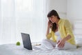 One pregnant european woman working from her home while she is sitting on a white bed at day time Royalty Free Stock Photo